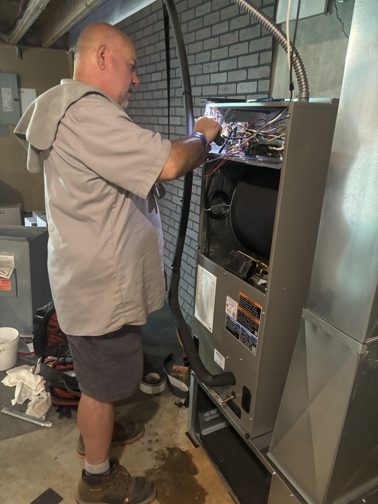 Robert Hollander servicing a furnace's wiring inside a Kansas City home